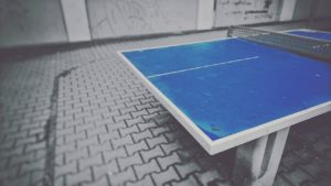 A photograph of a ping pong table in a concrete, gritty, city-style backdrop