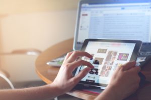 An image showing a person using a tablet and laptop to create an effective digital marketing campaign